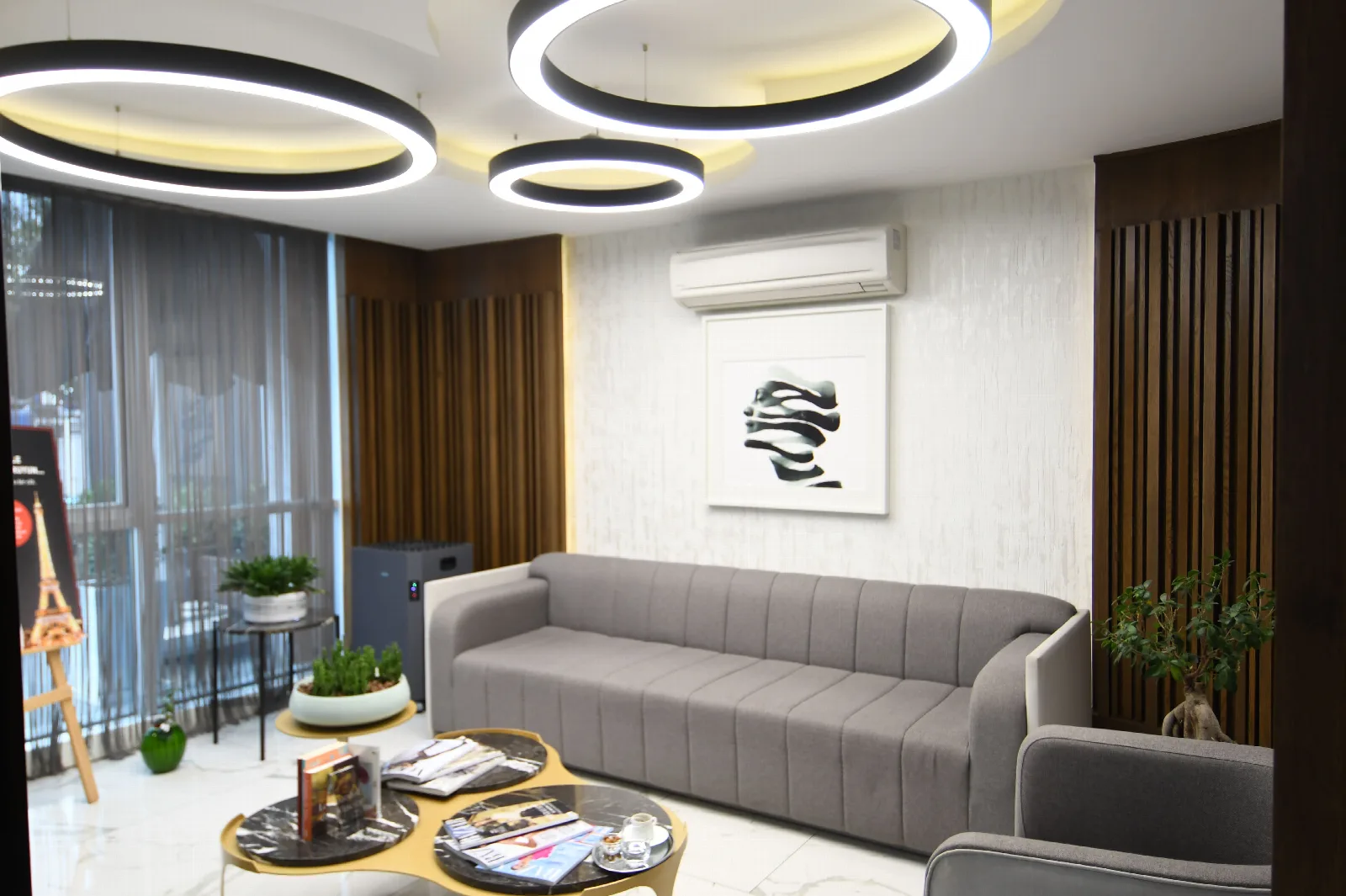 The waiting lounge at The More Clinics: a grey sofa under ring lighting, with a balcony beyond the curtains.