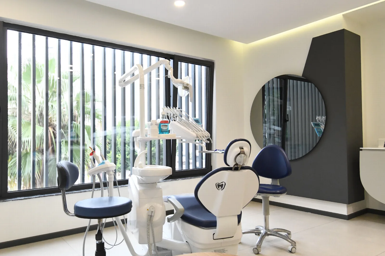 A treatment room at The More Clinics, the chair and unit beside a window looking onto palm trees.